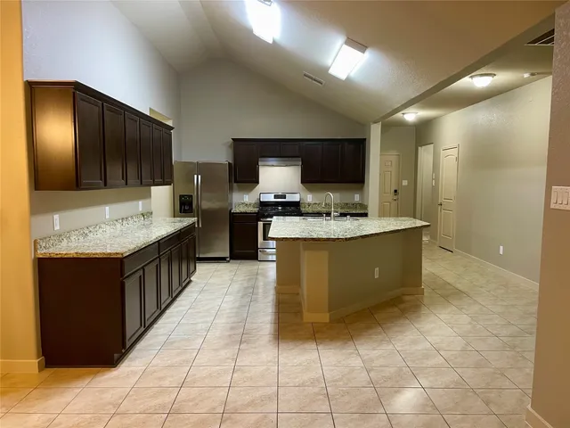 a large kitchen with a stove a sink a counter space and cabinets