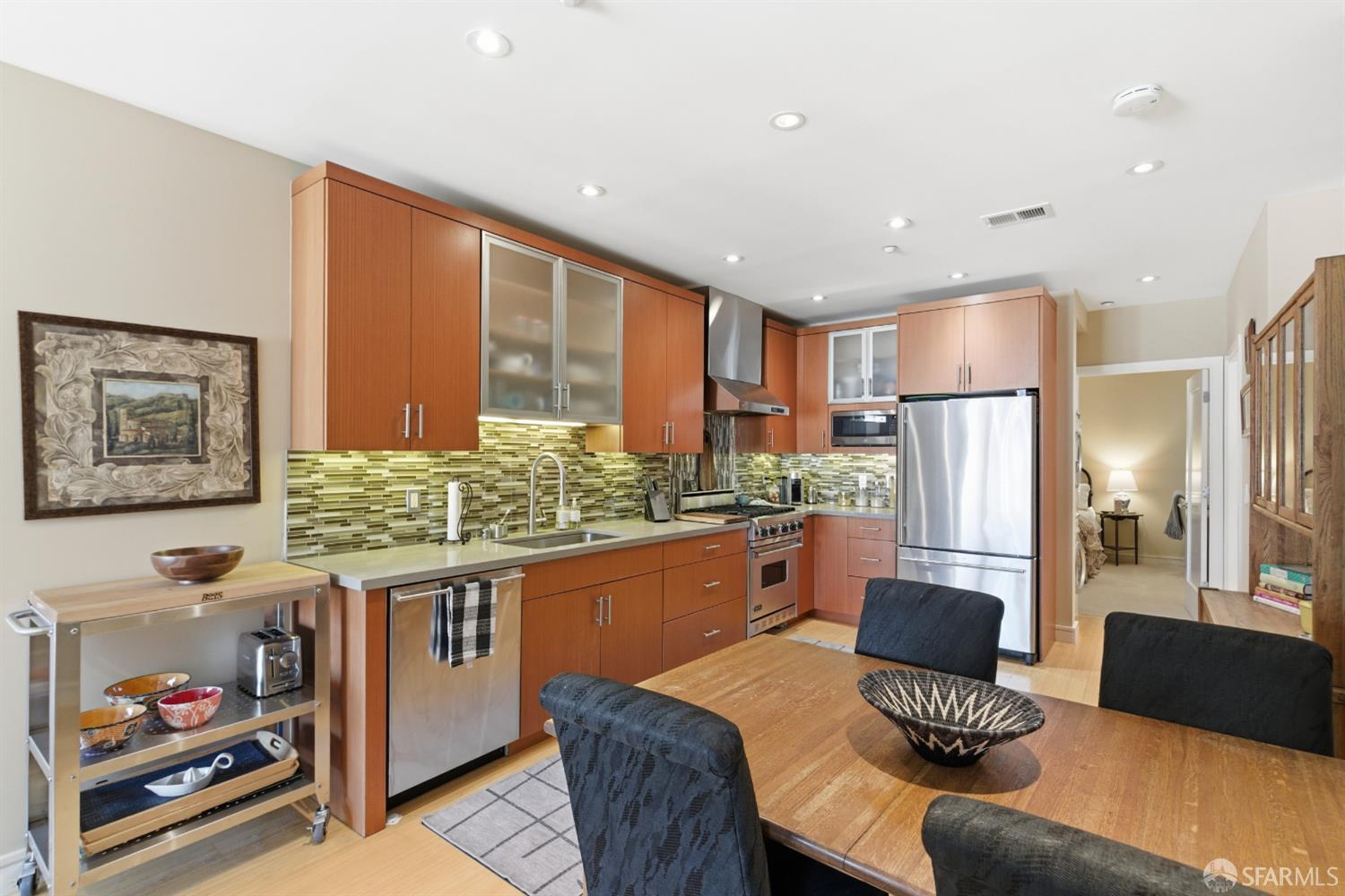 1725 Washington Street, Unit 9 San Francisco, CA 94109 - Photo 5 of 13 a kitchen with stainless steel appliances granite countertop a refrigerator a stove and a dining table with wooden floor