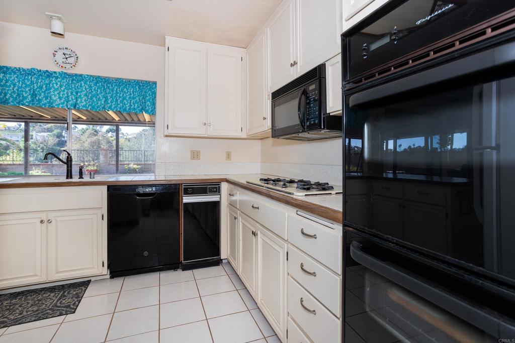 4427 Trieste Drive Carlsbad, CA 92010 - Photo 10 of 24 a kitchen with stainless steel appliances kitchen island granite countertop a stove and a microwave