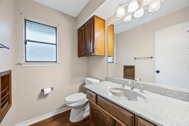 a bathroom with a granite countertop sink a toilet and mirror