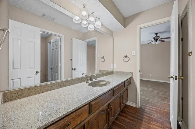 a bathroom with a granite countertop sink a mirror and shower