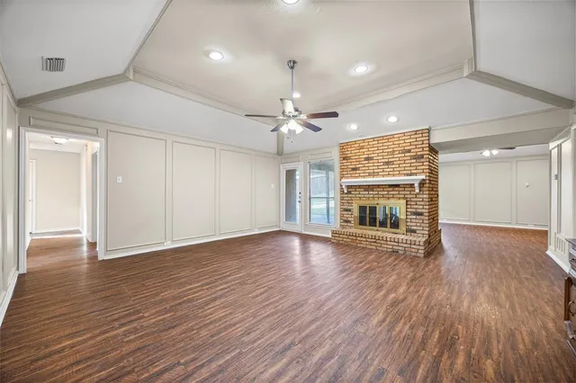 a view of an empty room with wooden floor fireplace and a window