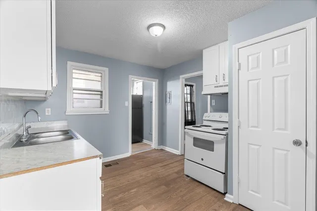 a kitchen with granite countertop white cabinets and white appliances