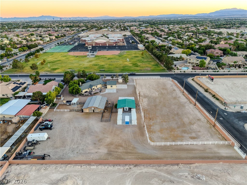 6460 Racel Street Las Vegas, NV 89131 - Photo 28 of 59 An expansive lot features equestrian structures and a large arena set against a distant mountain backdrop.