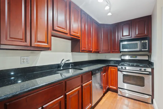 a kitchen with granite countertop wooden cabinets and stainless steel appliances