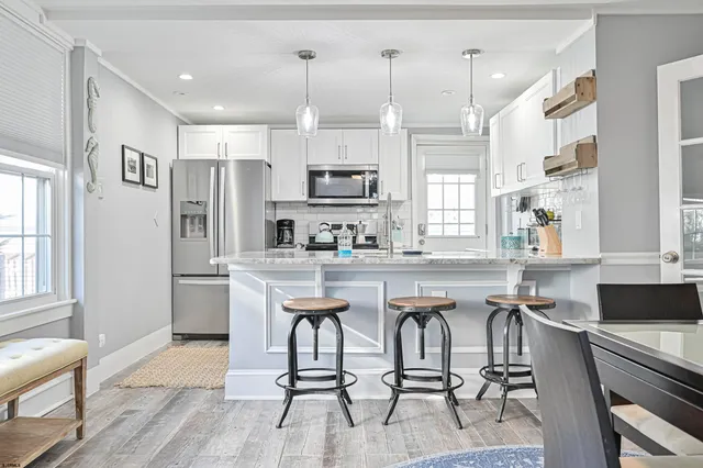 a kitchen with stainless steel appliances kitchen island granite countertop a table chairs refrigerator and microwave