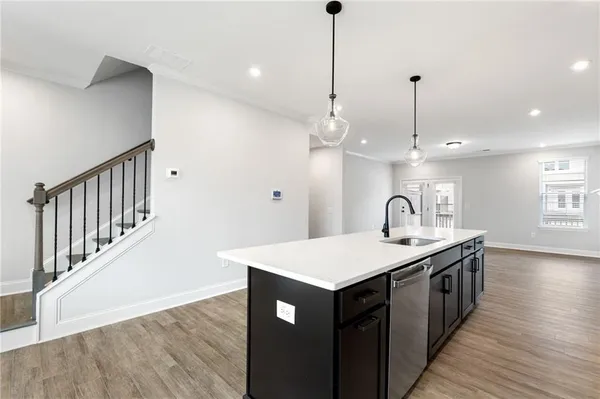 a kitchen with stainless steel appliances granite countertop a sink a chandelier and a wooden floor