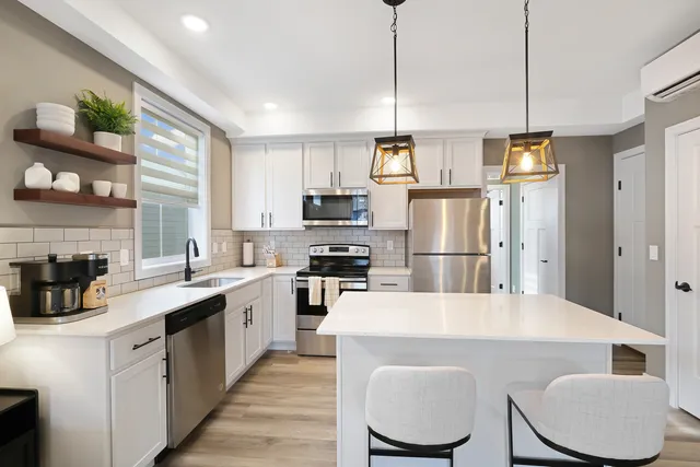 a kitchen with a refrigerator a stove a sink dishwasher a oven with white cabinets and wooden floor