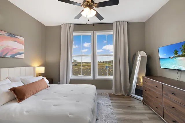 a bedroom with a bed flat screen tv and a large window