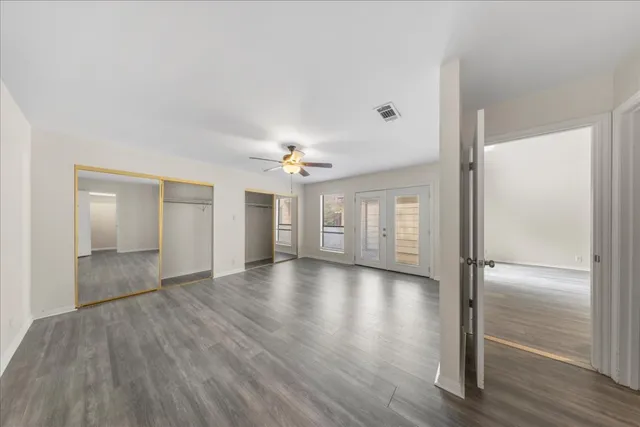 a view of an empty room with window and wooden floor
