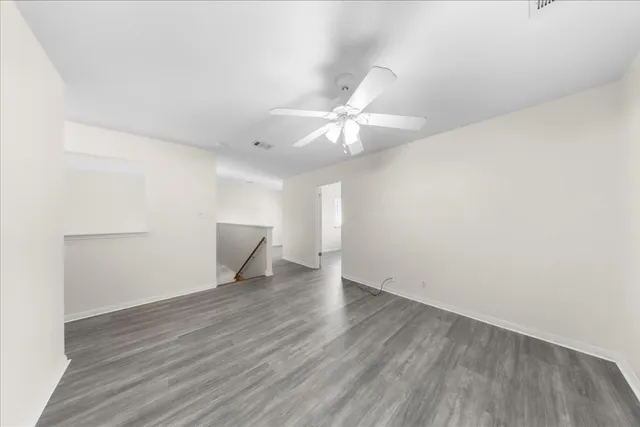 an empty room with wooden floor and fan