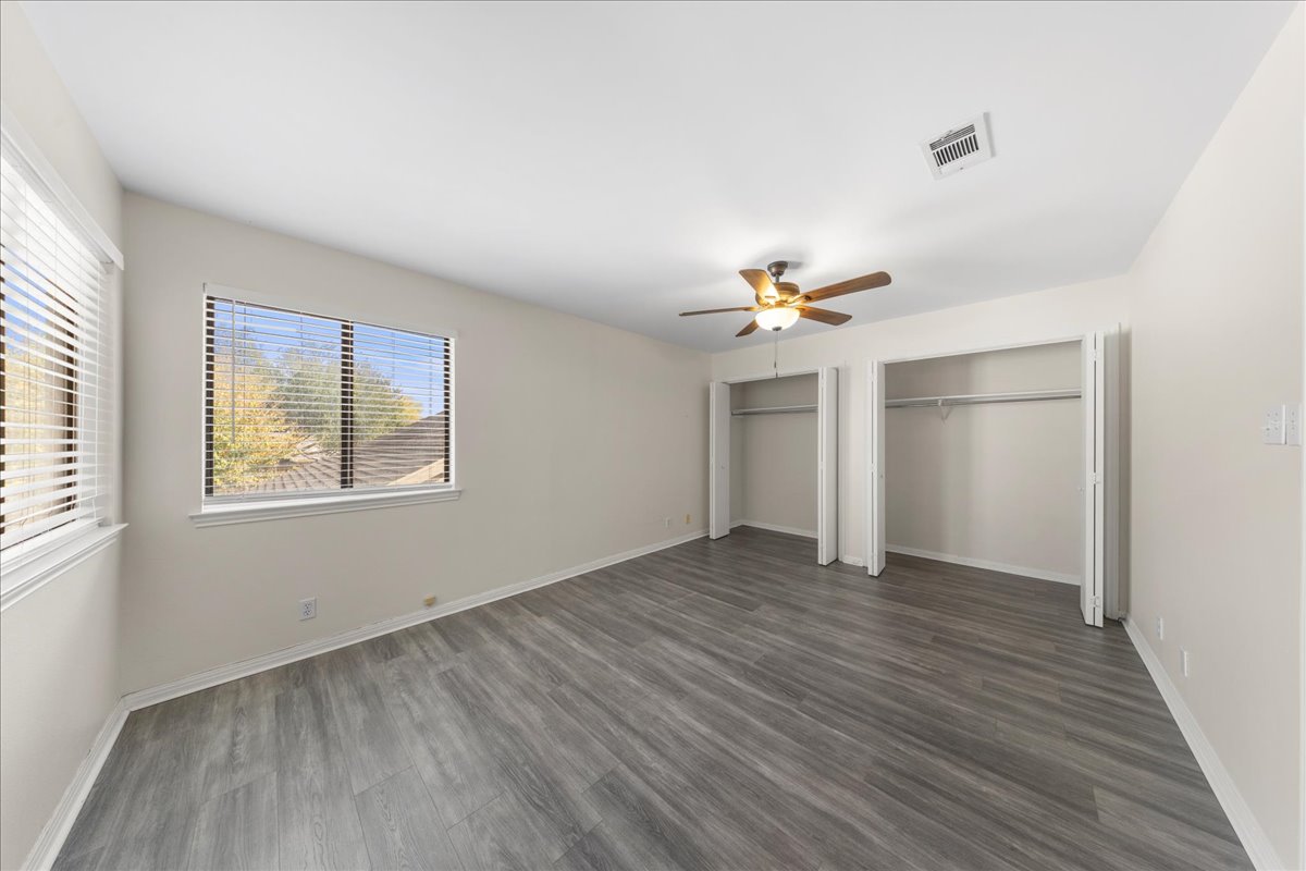 10900 Crown Colony Drive, Unit B Austin, TX 78747 - Photo 20 of 26 an empty room with wooden floor chandelier fan and windows