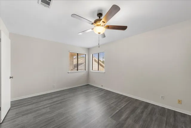an empty room with wooden floor and ceiling fan