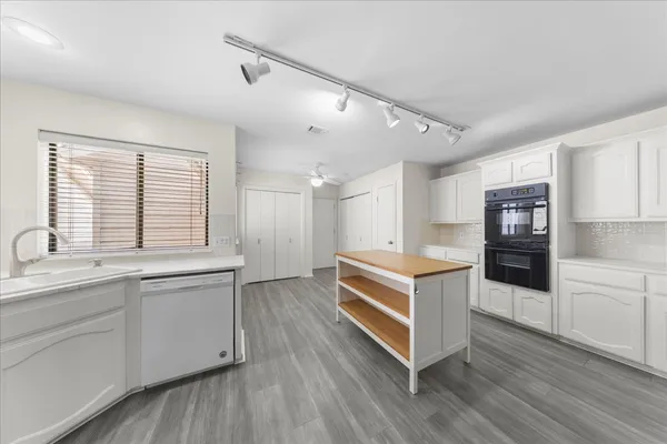 a kitchen with stainless steel appliances a sink and wooden floor