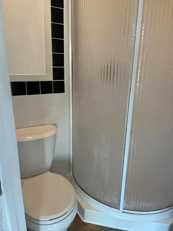 a white toilet sitting next to a shower