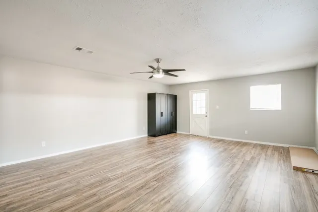 an empty room with wooden floor closet and windows
