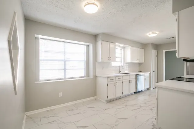 a kitchen with granite countertop cabinets stainless steel appliances a sink and a window