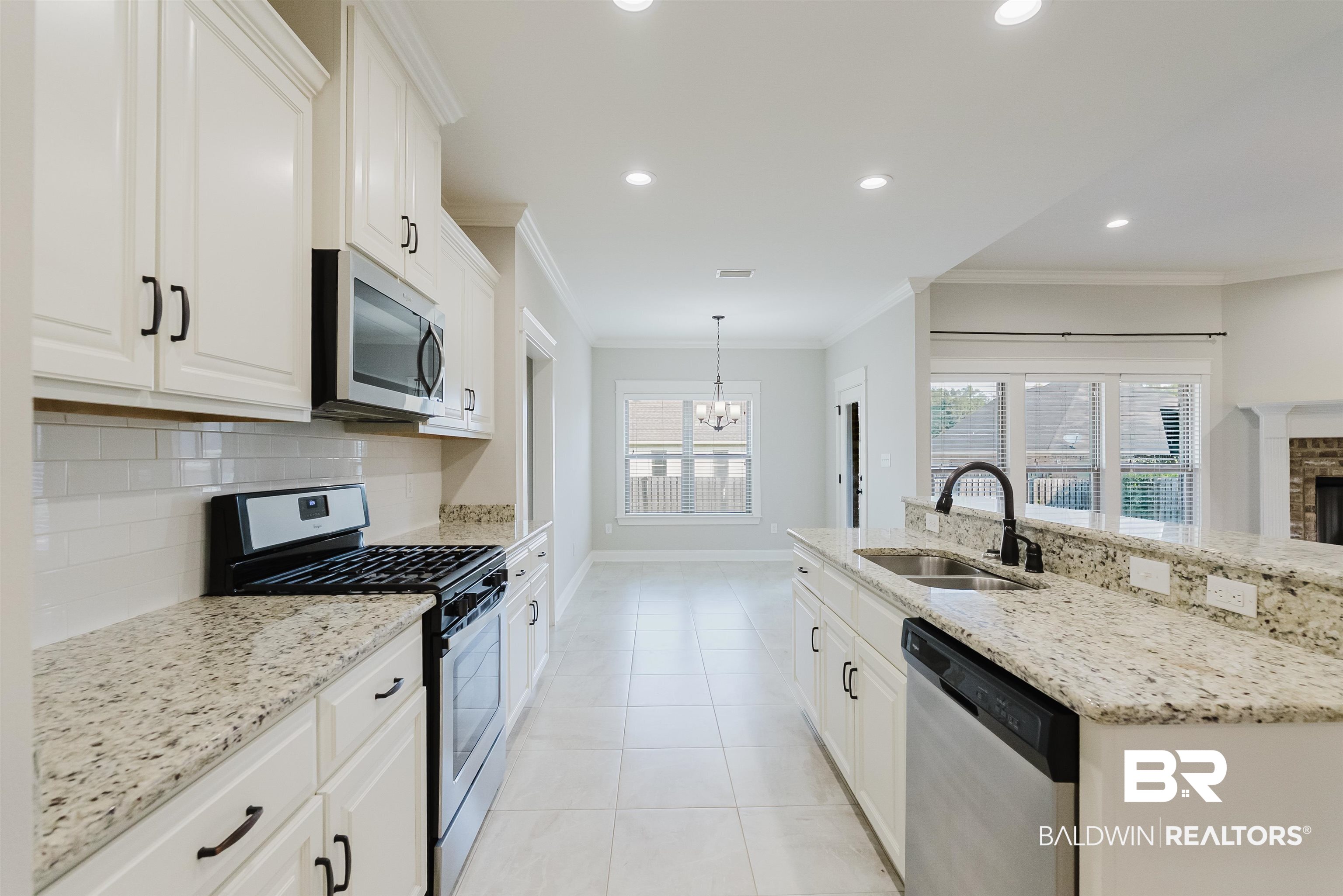 237 Hawthorne Circle Fairhope, AL 36532 - Photo 3 of 14 Kitchen featuring appliances with stainless steel finishes, white cabinetry, light stone counters, recessed lighting, and a chandelier