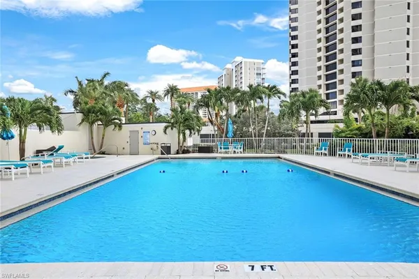 a view of a swimming pool with a lawn chairs and potted plants