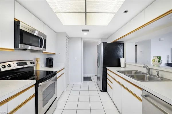 a kitchen that has a sink a microwave oven a stove and white cabinets