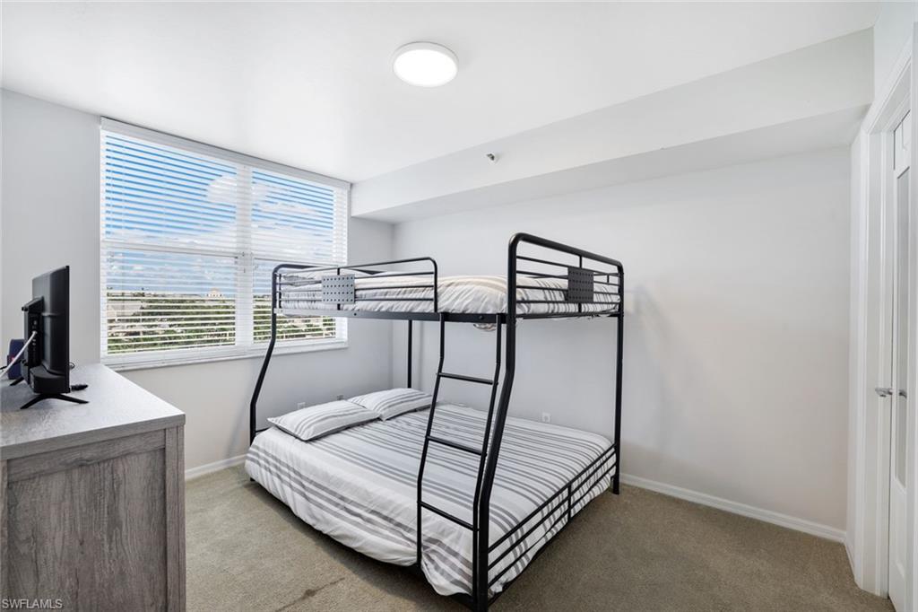 5550 Heron Point Drive, Unit 304 Naples, FL 34108 - Photo 10 of 19 a bedroom with three beds and a flat screen tv