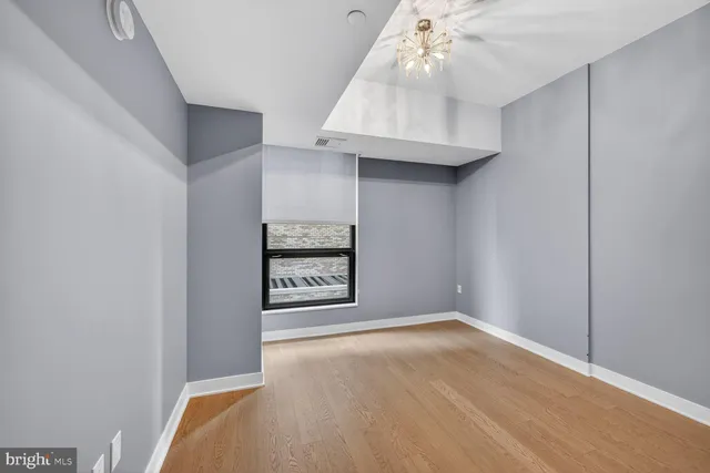 an empty room with chandelier fan and windows