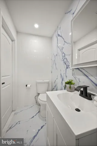 a bathroom with a granite countertop toilet a sink and a mirror