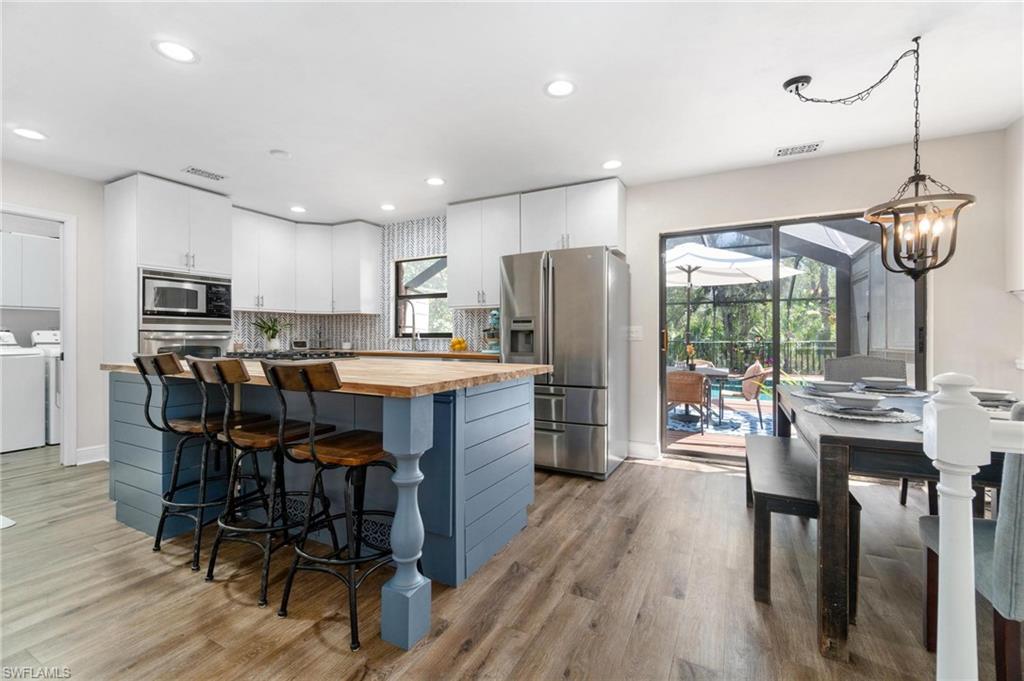 1041 29th Street Southwest Naples, FL 34117 - Photo 13 of 50 a kitchen with stainless steel appliances kitchen island granite countertop a table chairs refrigerator and cabinets