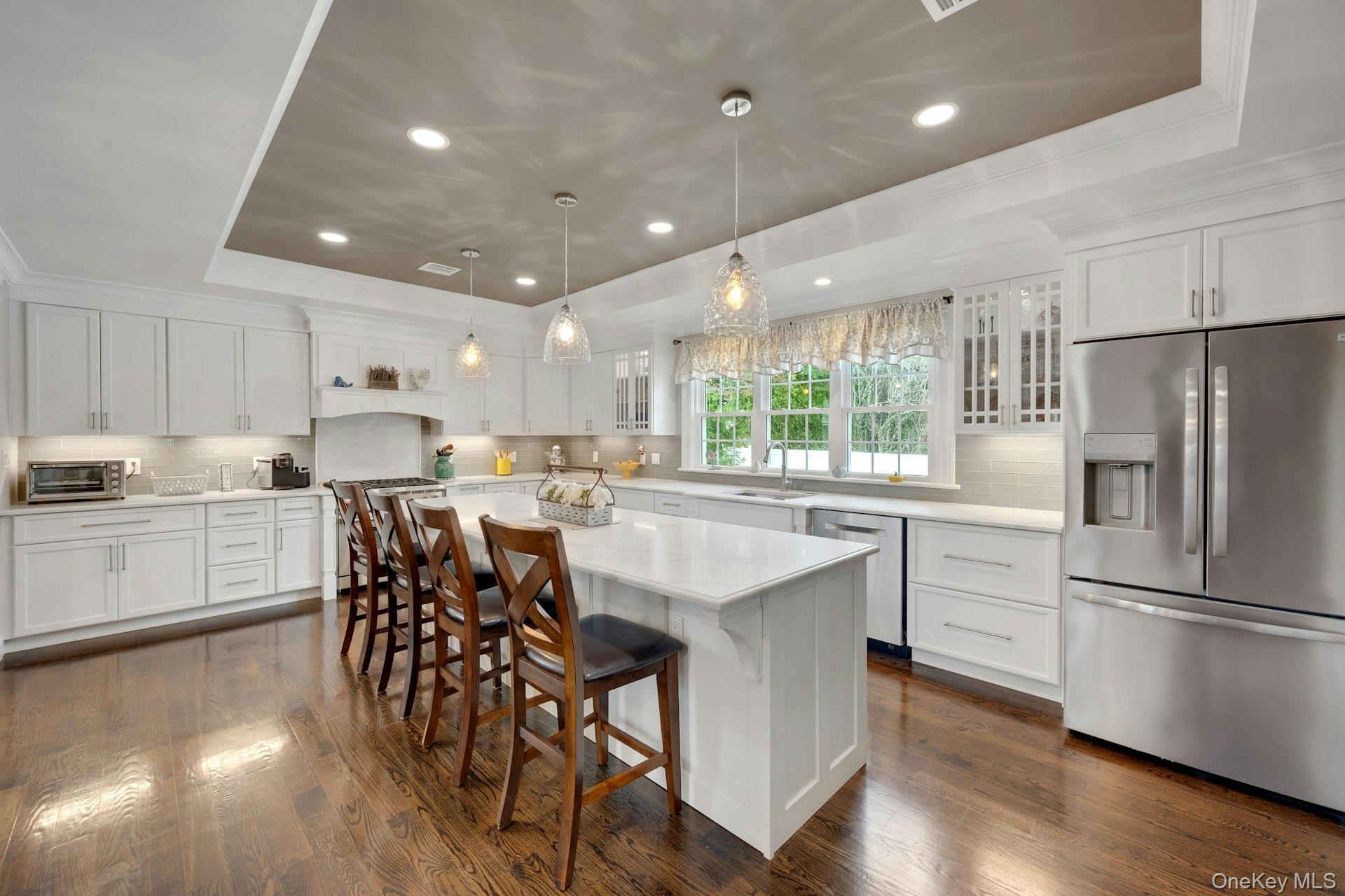155 Hilburn Road Scarsdale, NY 10583 - Photo 4 of 35 a kitchen with stainless steel appliances a table chairs refrigerator microwave and wooden floor