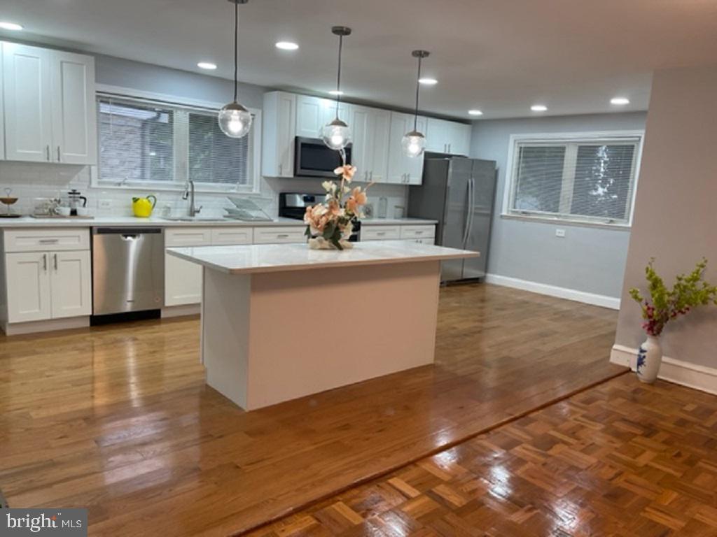 a kitchen with kitchen island stainless steel appliances a sink a counter top space cabinets and a window