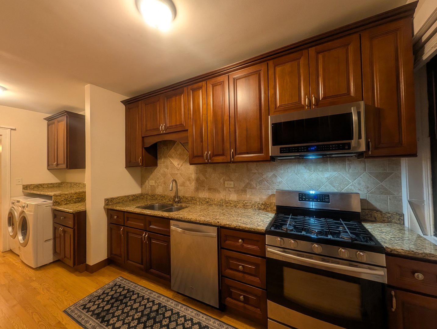 1419 East 56th Street, Unit 1 Chicago, IL 60637 - Photo 10 of 35 a kitchen with stainless steel appliances granite countertop a stove microwave and sink