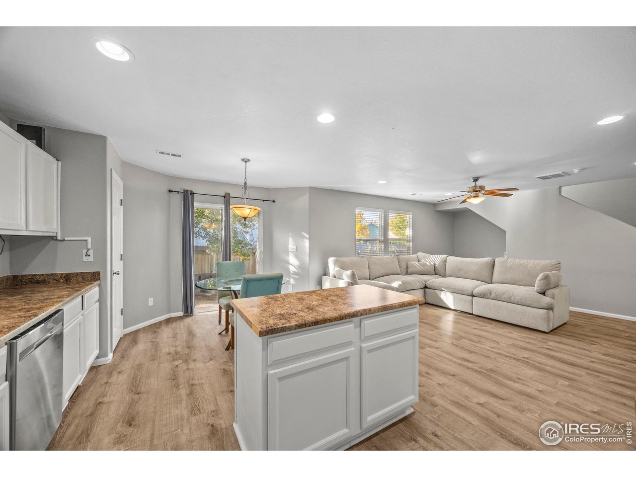 10688 Durango Place Longmont, CO 80504 - Photo 11 of 49 a kitchen with a stove a sink dishwasher and a dining table with wooden floor