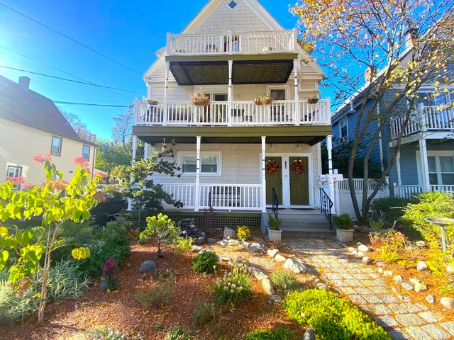 a front view of a house with a large window and potted plants