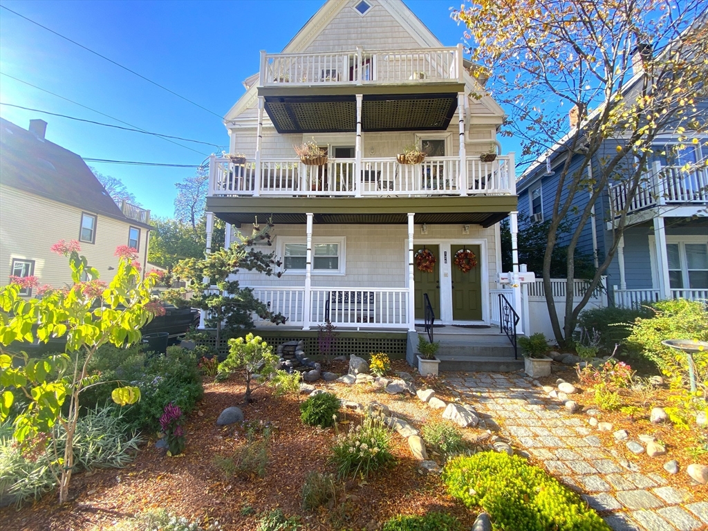 a front view of a house with a large window and potted plants