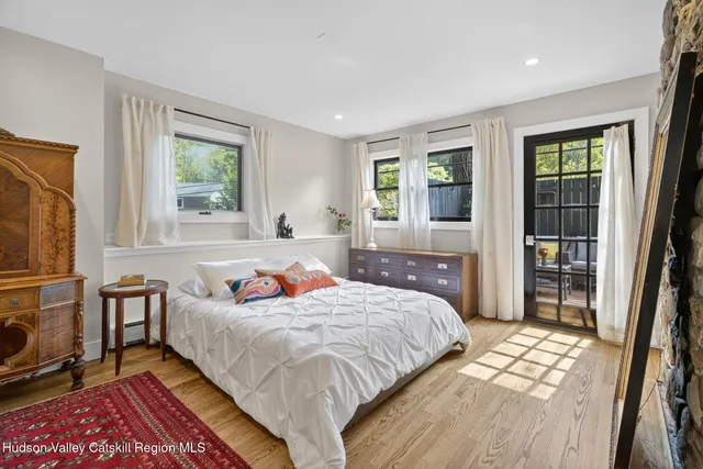 a bedroom with a bed wooden floor and a large window