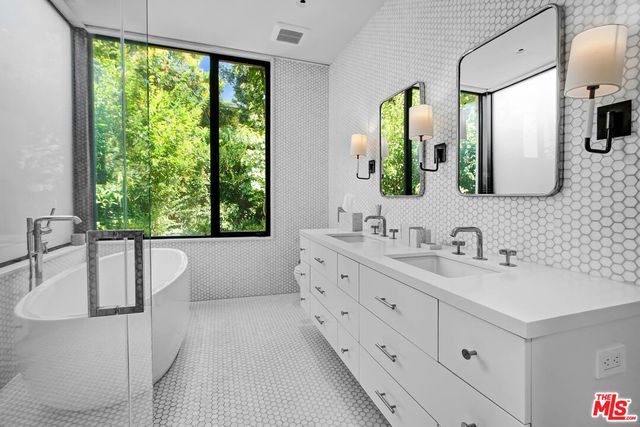 a bathroom with a double vanity sink a mirror and a bathtub