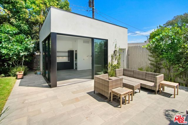 a patio with a table and chairs and potted plants