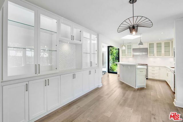 a kitchen with white cabinets and wooden floor