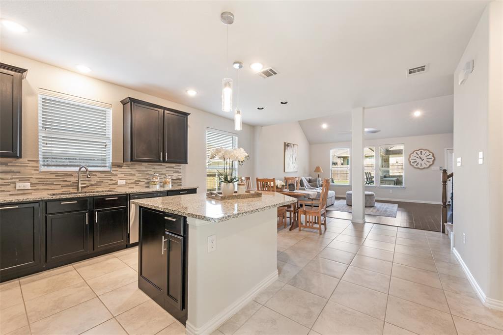 Kitchen featuring an island with stone countertops, dark wood-finish cabinetry, a tile backsplash, and recessed lighting