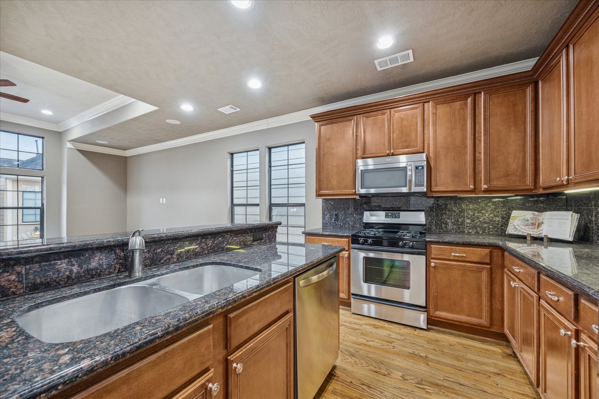 1376 Studer Street Houston, TX 77007 - Photo 11 of 38 Kitchen features stainless steel appliances, granite countertops, and rich wood cabinetry. It offers an open layout with ample natural light, a double sink, and a built-in microwave. I