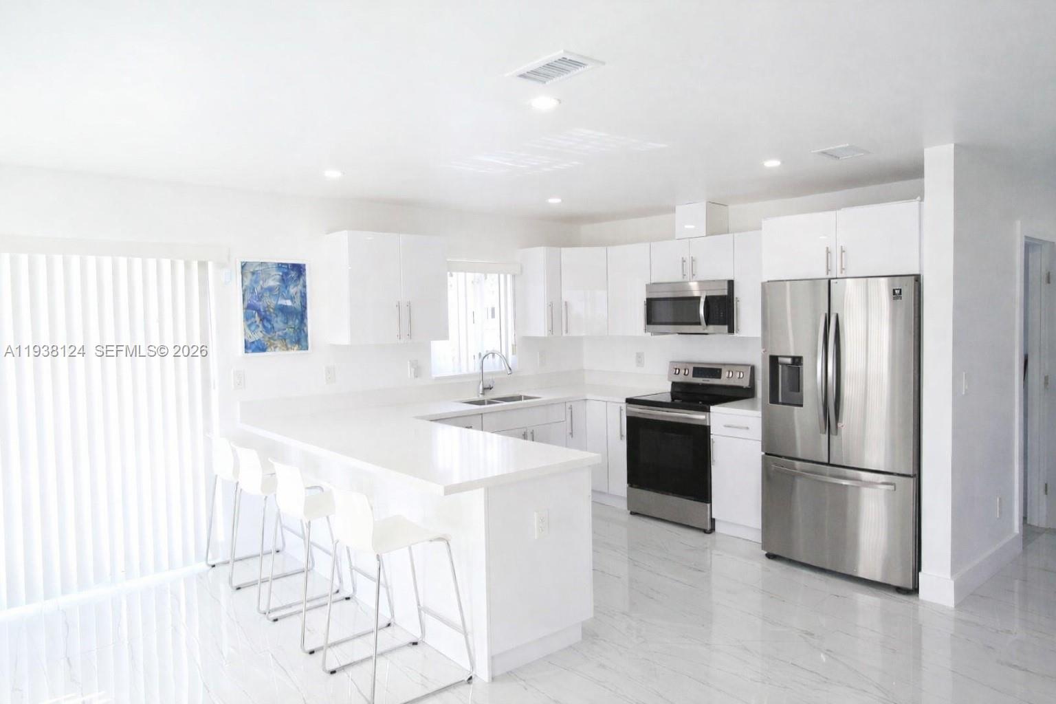 798 West 31st Street Hialeah, FL 33012 - Photo 4 of 15 a kitchen with white cabinets and stainless steel appliances