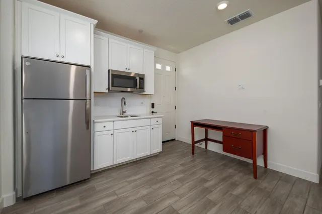 a large kitchen with stainless steel appliances granite countertop a stove a sink dishwasher and a oven with white cabinets