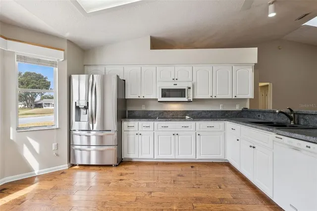a large kitchen with granite countertop a stove top oven a sink a counter space and cabinets