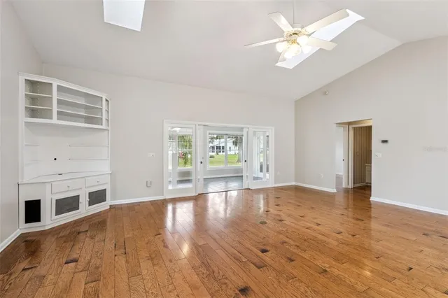 a view of an empty room with window and wooden floor