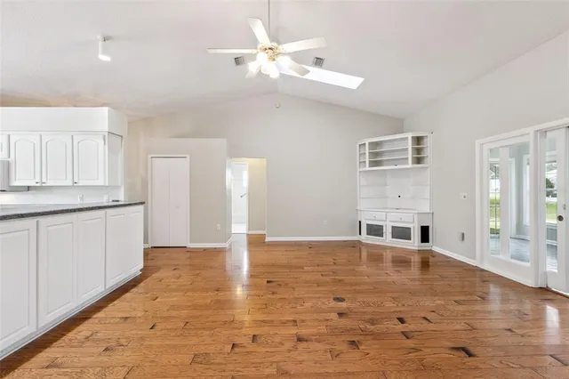 a view of an empty room with window and wooden floor