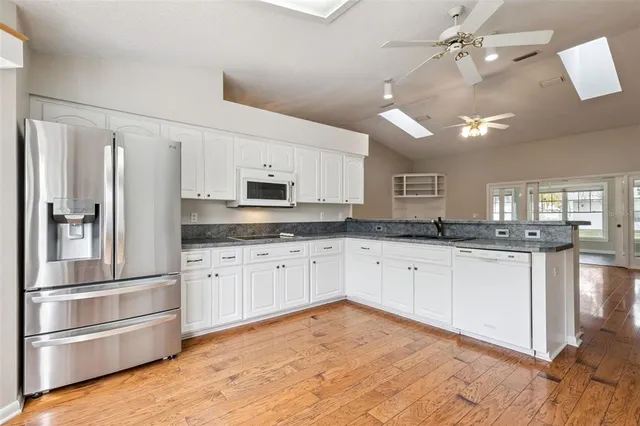 a kitchen with granite countertop a refrigerator sink and cabinets
