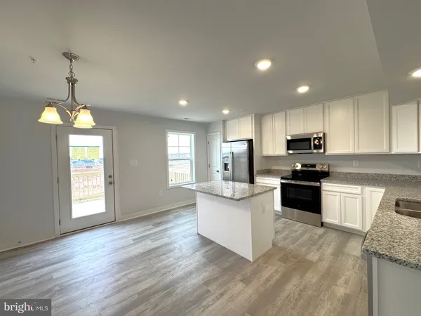 a kitchen with stainless steel appliances granite countertop a refrigerator a sink dishwasher a stove and white countertops with wooden floor