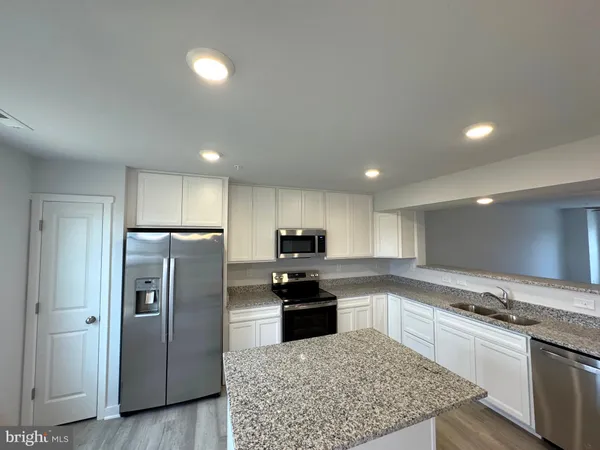 a kitchen with granite countertop a refrigerator and a stove top oven