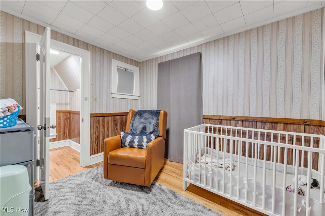 3729 Grosvenor Road Cleveland, OH 44118 - Photo 23 of 39 Bedroom with a crib, wood finished floors, and wallpapered walls