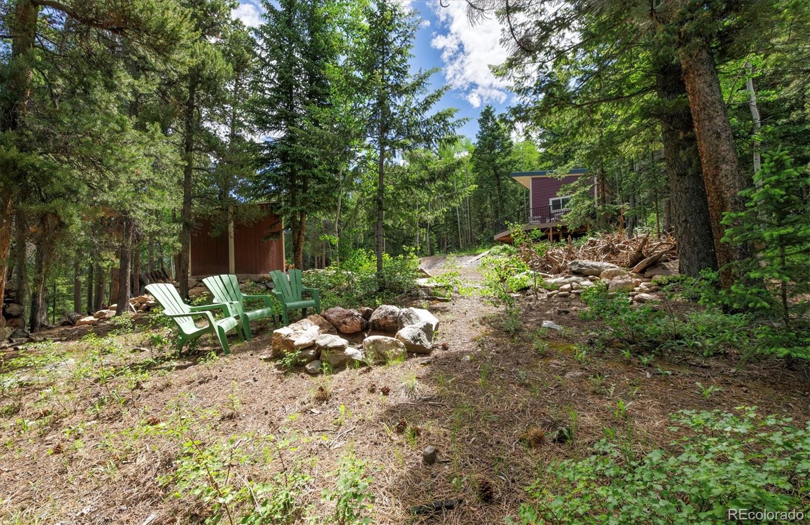 3450 Smith Hill Road Black Hawk, CO 80422 - Photo 24 of 26 a backyard of a house with table and chairs wooden fence and plants
